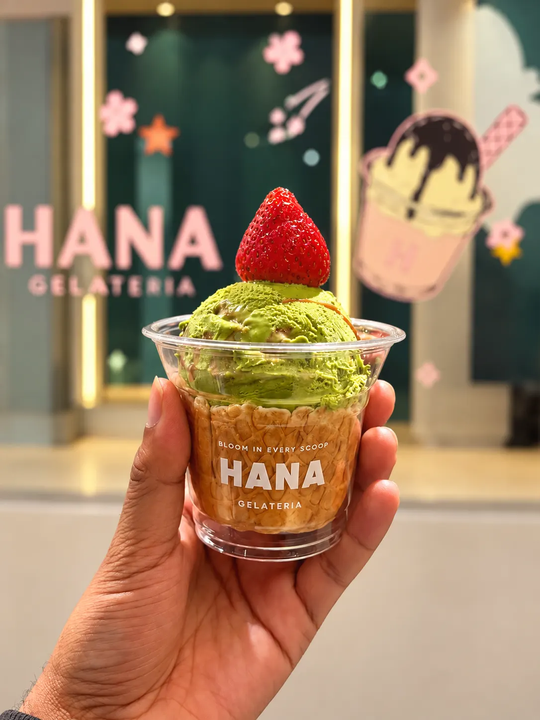 Strawberry matcha gelato in a waffle cup, topped with a strawberry